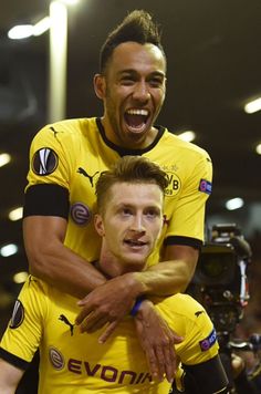 two soccer players are hugging each other in the middle of a crowd at a stadium