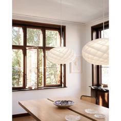 a dining room table with plates on it and two lamps hanging from the ceiling above