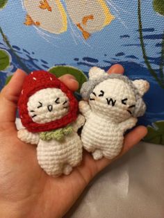 two small crocheted animals are held in someone's hand while wearing a red and white hat