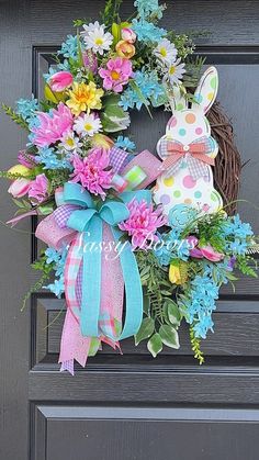 a wreath with flowers and an easter bunny sitting on it's front door handle