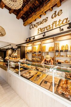 there is a woman behind the counter in this bakery shop that sells breads and pastries