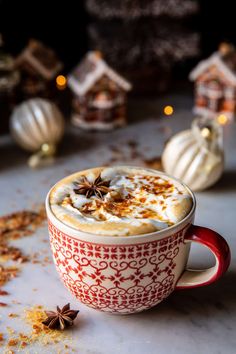 a cup of hot chocolate topped with whipped cream and star anise on a table