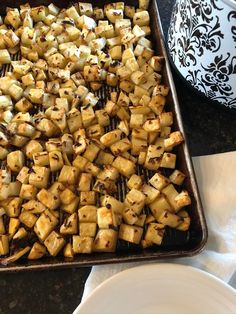 a pan filled with cooked potatoes on top of a table next to plates and utensils