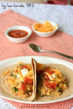 two tortillas on a plate with salsa and sour cream in the back ground