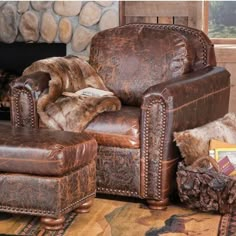 a brown leather chair and ottoman in front of a fire place with fur on it