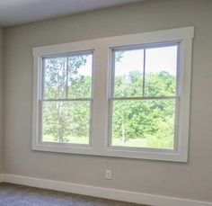 an empty room with two windows and carpeted flooring in front of the window