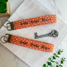 two personalized orange polka dot key fobs on a white napkin with green leaves