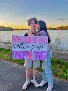 two girls standing next to each other holding a sign that says, will you be my future perfect prom date?