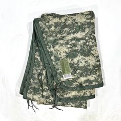 two green and white camouflage cloths laying on top of each other, one folded up