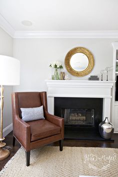 a living room with a chair, fireplace and mirror