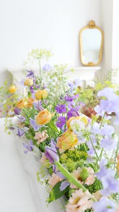 a bunch of flowers that are sitting in a vase on a ledge next to a mirror