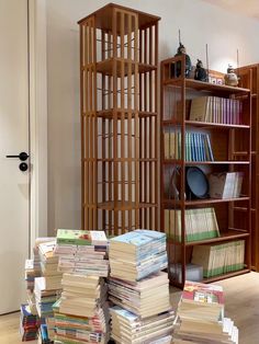 a stack of books sitting on top of a wooden floor next to a book shelf