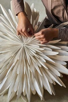 a woman is working on a sculpture made out of paper