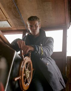 a man is sitting on the deck of a boat holding a steering wheel with both hands