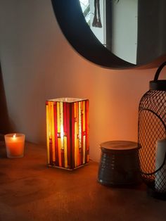 a candle is sitting next to a mirror on a table