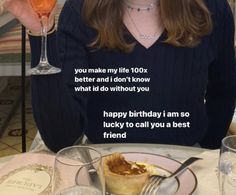 a woman sitting at a table with a plate of food and drink in front of her