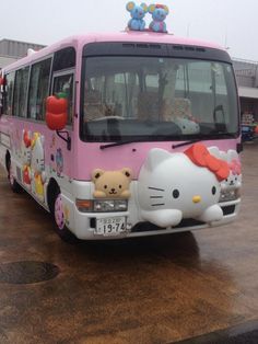 a hello kitty bus parked in a parking lot with an apple on the top of it