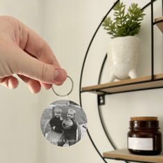 a person holding a keychain with a photo on it and some jars in the background