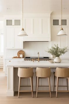 three stools sit at the center of a kitchen island with white cabinets and drawers