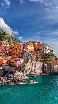 the colorful village is perched on top of a cliff above the water's edge