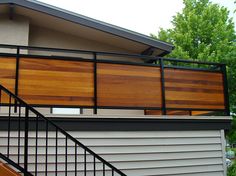 a house that has some wood on the outside and metal railings in front of it