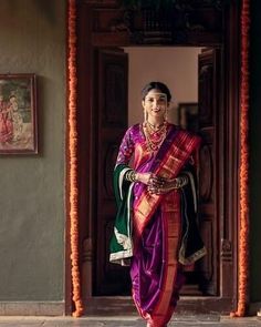 a woman in a purple and green sari is walking into the room with her hand on her hip