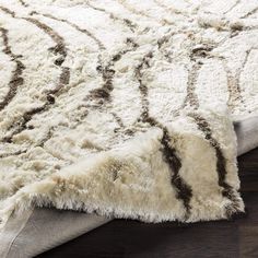 a white rug with brown lines on the top and bottom is laying on a wooden floor