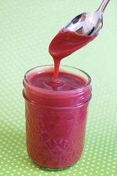 a spoon is pouring ketchup into a jar