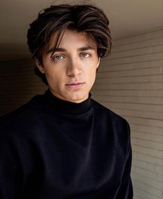 a young man in a black turtle neck sweater looking at the camera with an intense look on his face