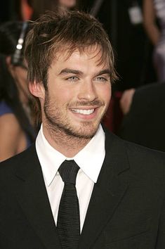 a smiling young man in a suit and tie at an awards ceremony, looking to the side