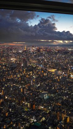 an aerial view of the city lights and buildings at night from a window with a panoramic view