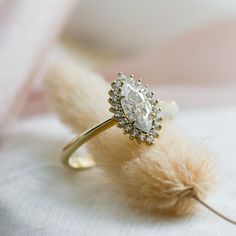 a diamond ring sitting on top of a piece of fabric with feathers in the foreground