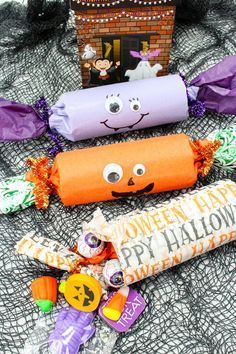 some candy wrapped in paper on top of a bed with halloween decorations and candies