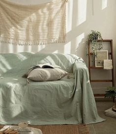 a living room with a couch covered in a light green blanket and pillows on top of it