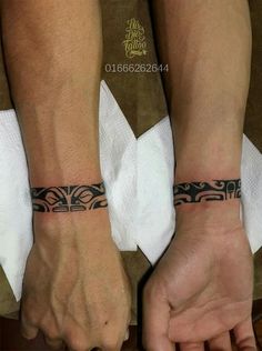 two people holding hands with tattoos on their wrists and wristbands, both wearing white napkins