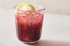 a glass filled with red liquid and a lemon wedge