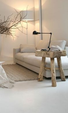 a living room with white furniture and a tree branch on the table in front of it