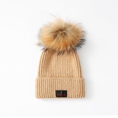 a beige hat with a brown fur pom