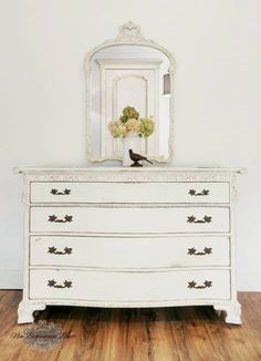 a white dresser with flowers and a mirror on top