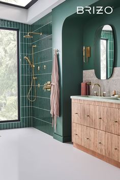 a bathroom with green tiles and gold fixtures on the wall, along with a large mirror