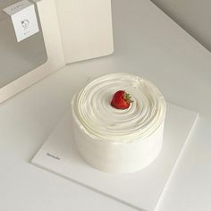 a white cake sitting on top of a table next to a box with a strawberry on it