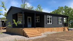 a small black house with steps leading up to the front door and windows on each side