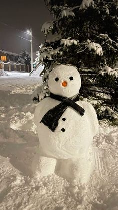 a snowman is standing in the snow next to a tree