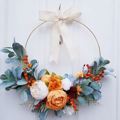 a wreath with flowers and leaves hanging on a door