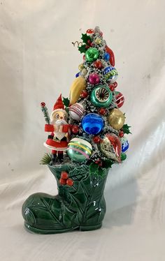 a christmas tree made out of glass ornaments on a white background with a green boot