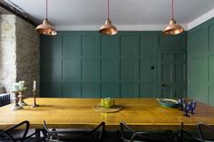 a wooden table with four chairs and three lights hanging from it's ceiling in a dining room