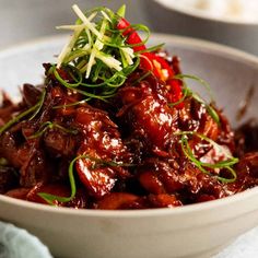 a close up of a bowl of food with meat and vegetables on top of it