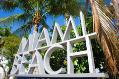 a sign that says welcome to the beach with palm trees in the background