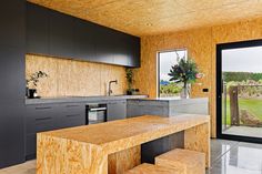 a kitchen with wooden walls and flooring next to a sliding glass door that leads outside