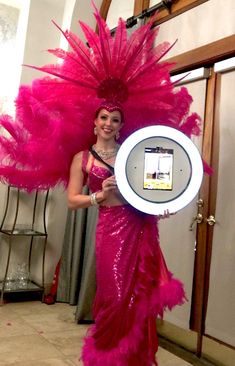 a woman in a pink feathered dress holding up a white plate with a cell phone on it